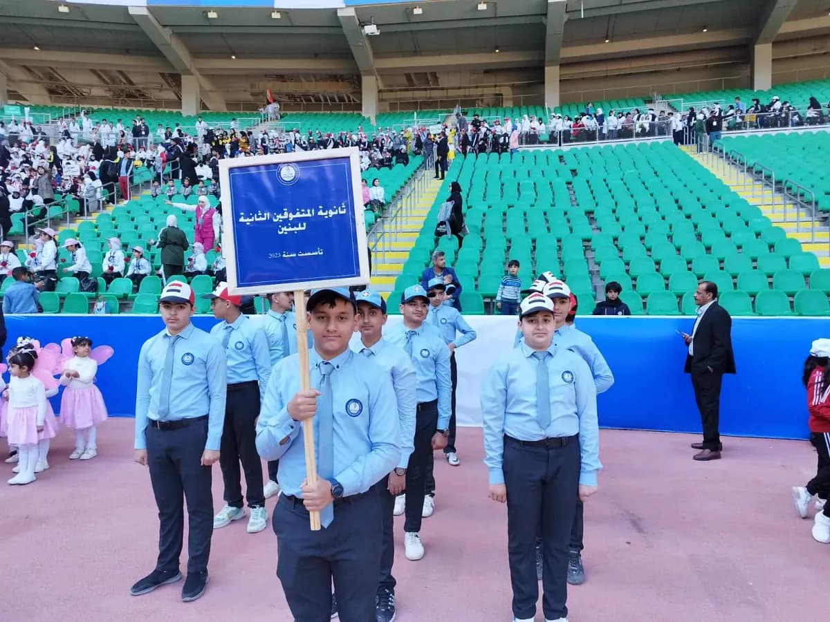 طلاب ثانوية المتفوقين الثانية يحملون لافتة المدرسة في الملعب